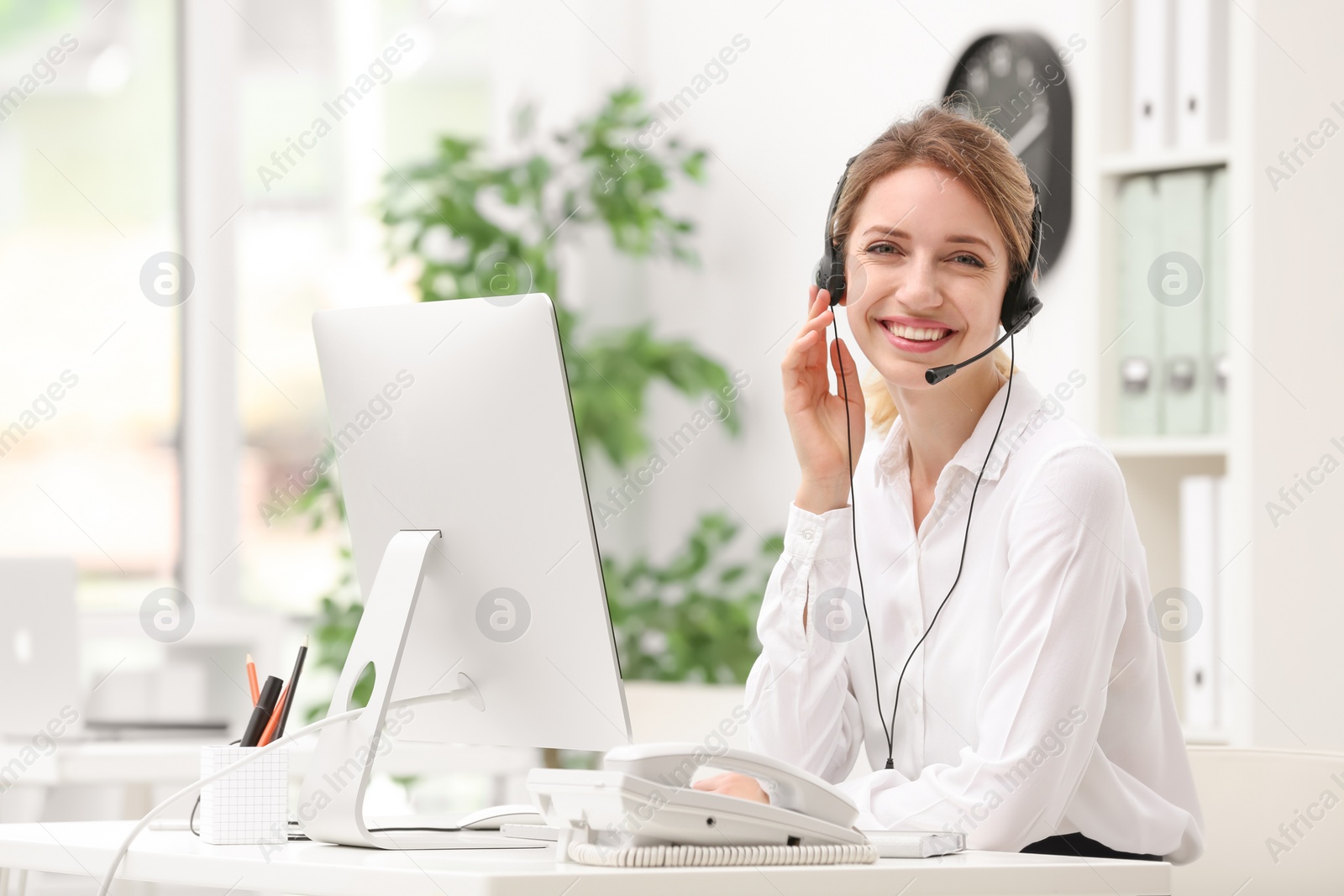 Photo of Female receptionist with headset at desk in office