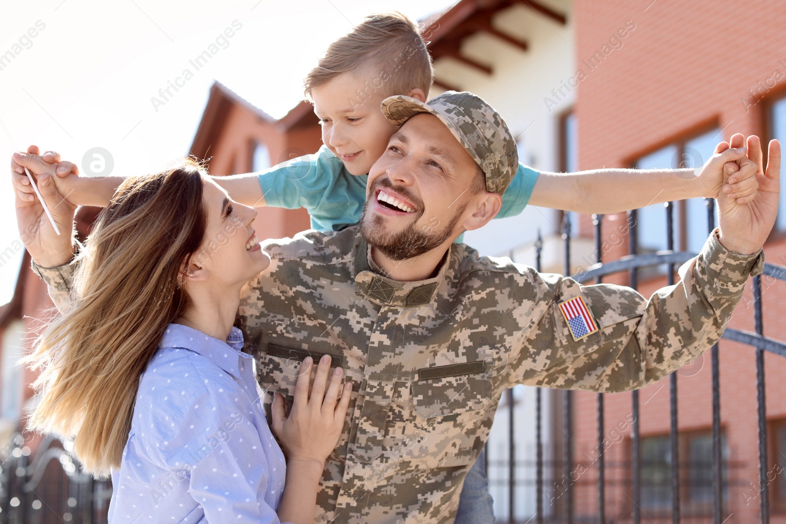 Photo of Male soldier reunited with his family outdoors. Military service