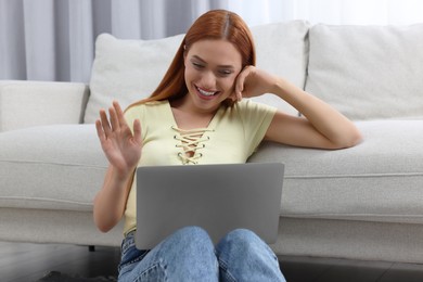 Photo of Woman waving hello during video chat via laptop at home