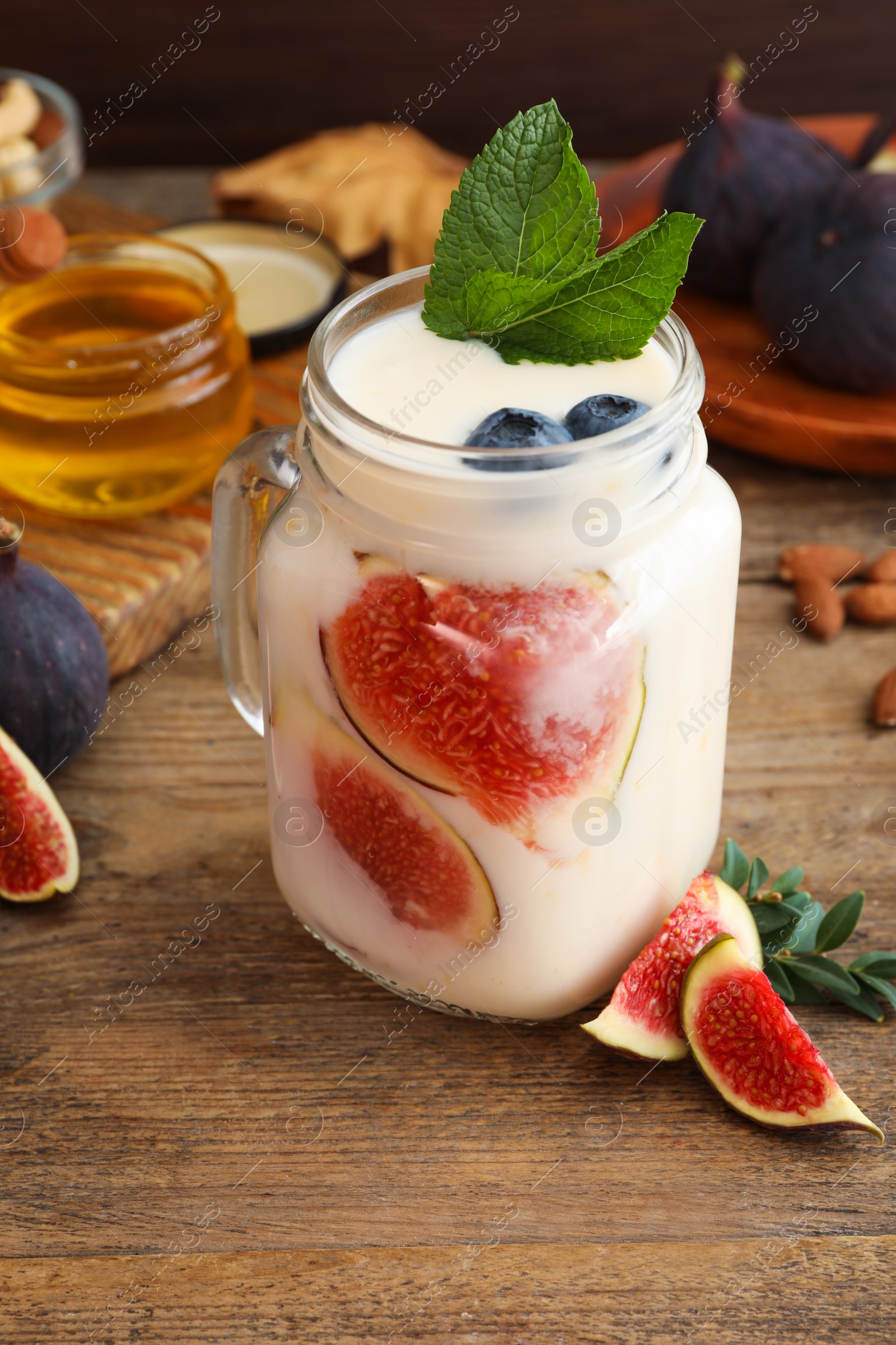 Photo of Delicious fig smoothie in mason jar on wooden table