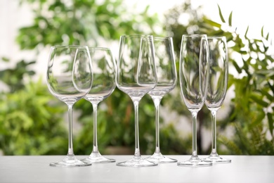 Photo of Set of clean glasses on grey table against blurred background