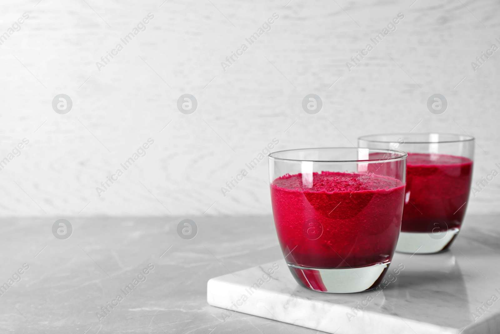 Photo of Glasses of fresh beet juice on marble board