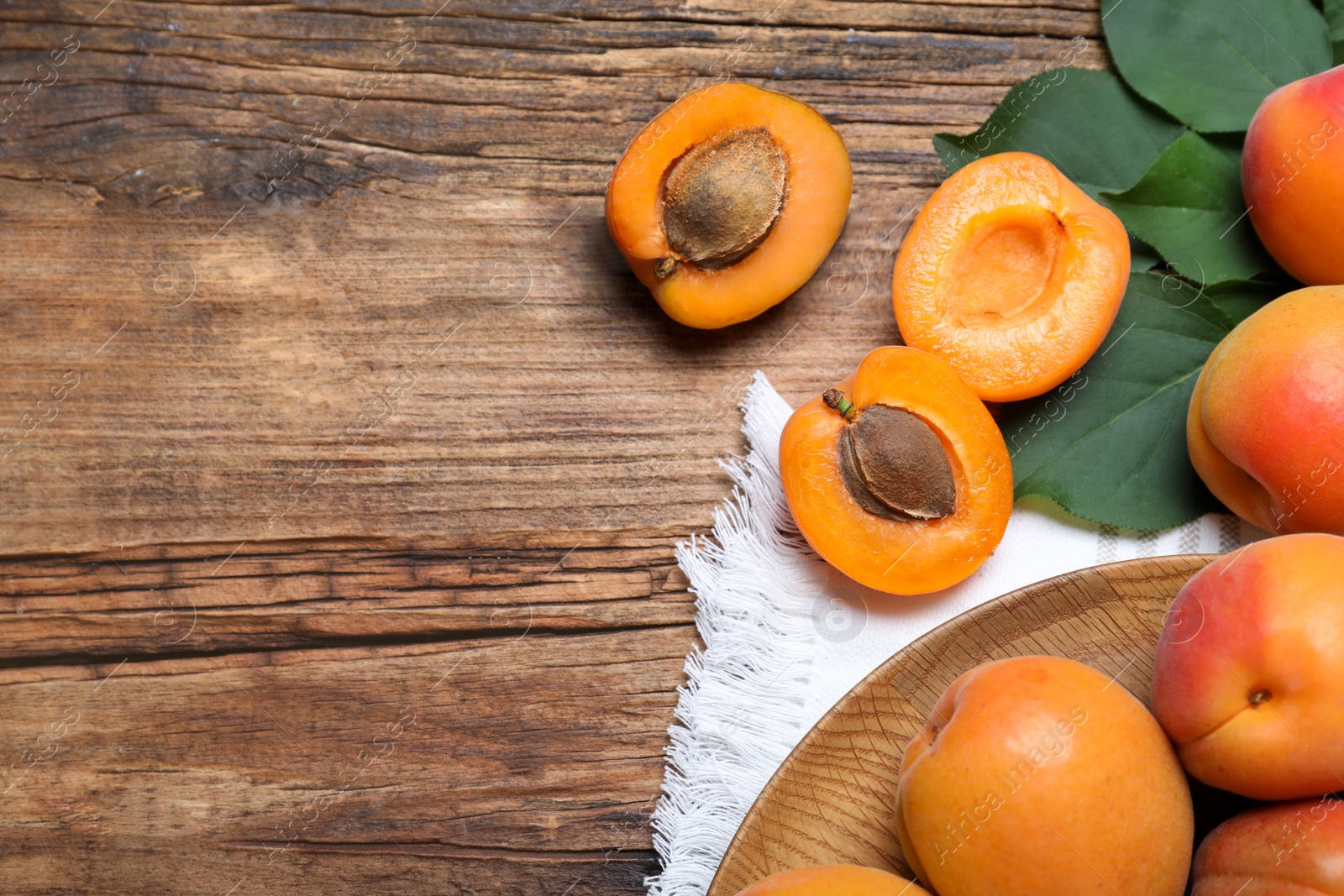 Photo of Delicious fresh ripe apricots on wooden table, flat lay. Space for text