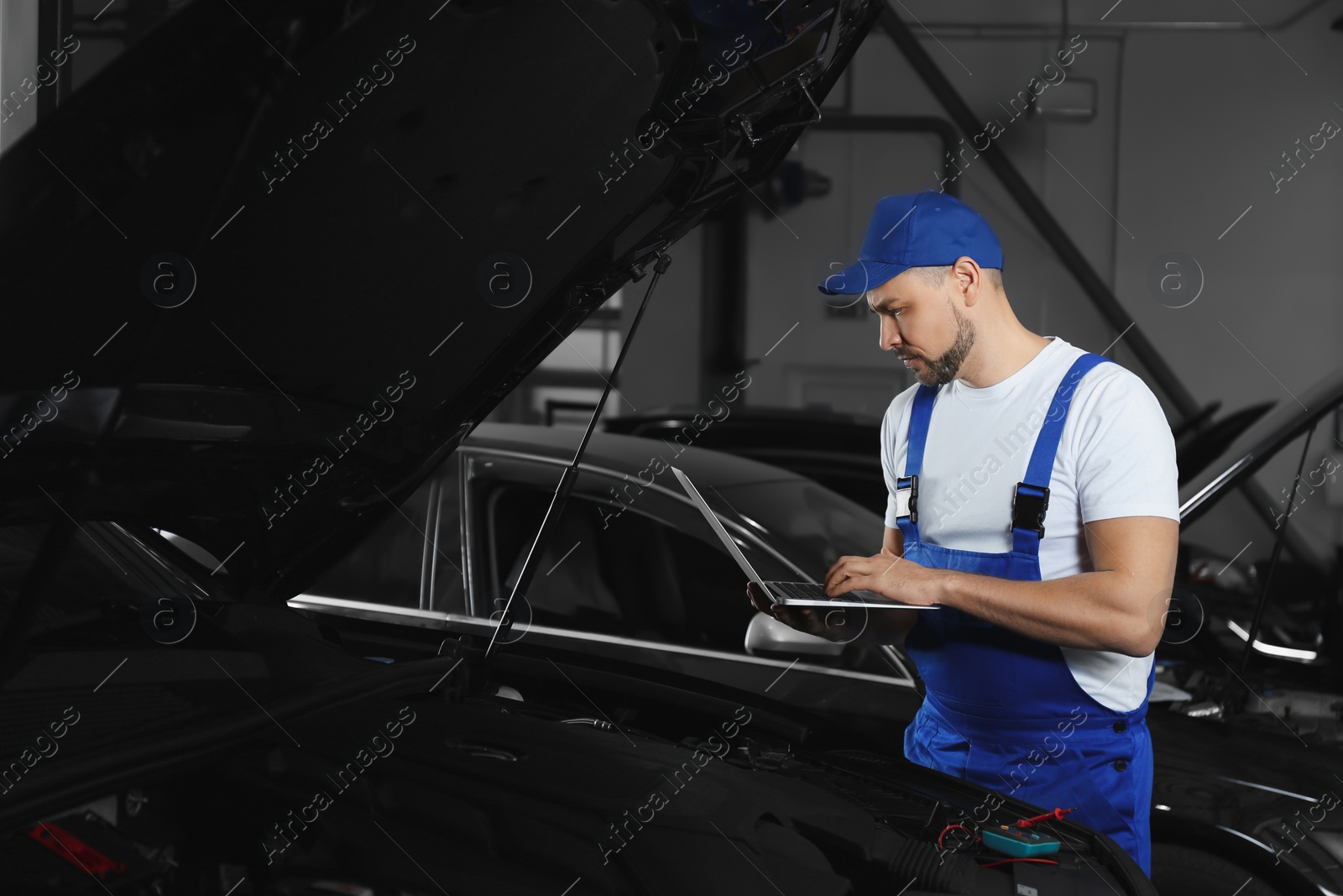 Photo of Mechanic with laptop doing car diagnostic at automobile repair shop