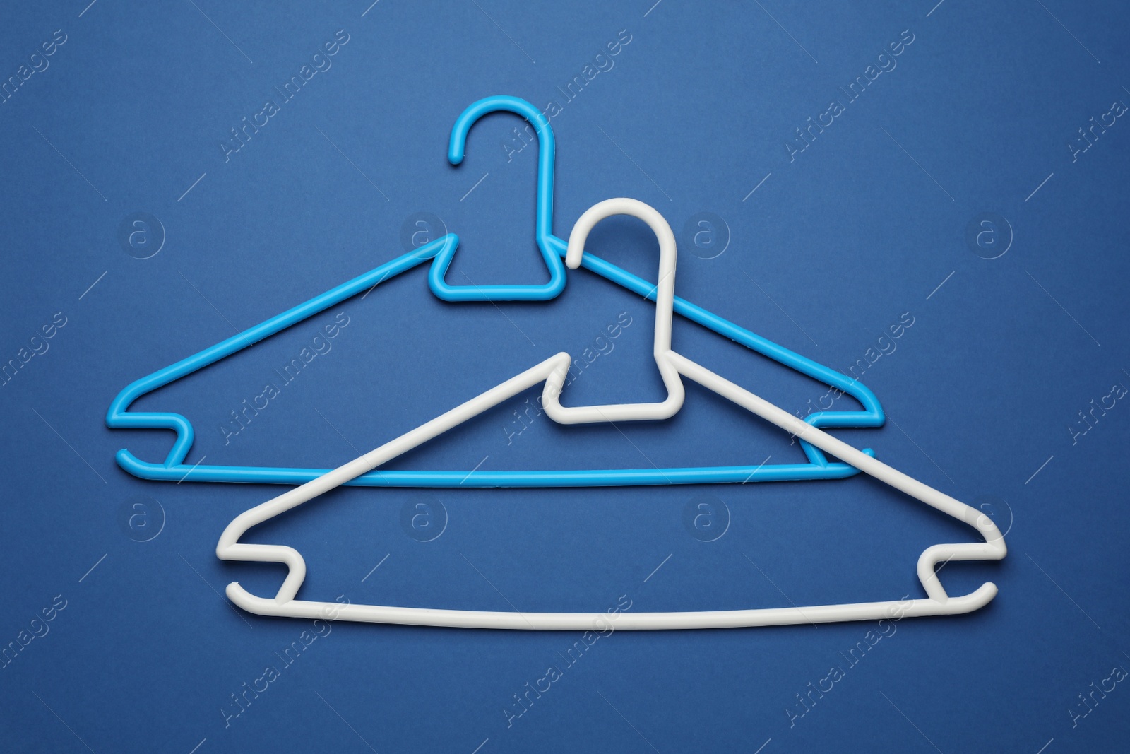 Photo of Empty clothes hangers on blue background, flat lay