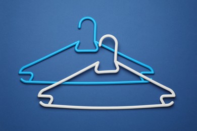 Empty clothes hangers on blue background, flat lay