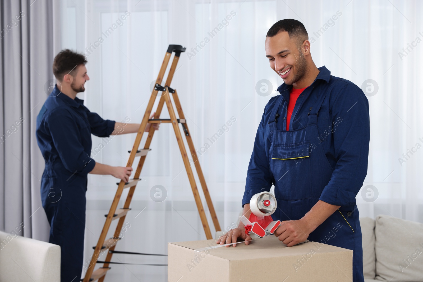 Photo of Male mover packing box with adhesive tape in house