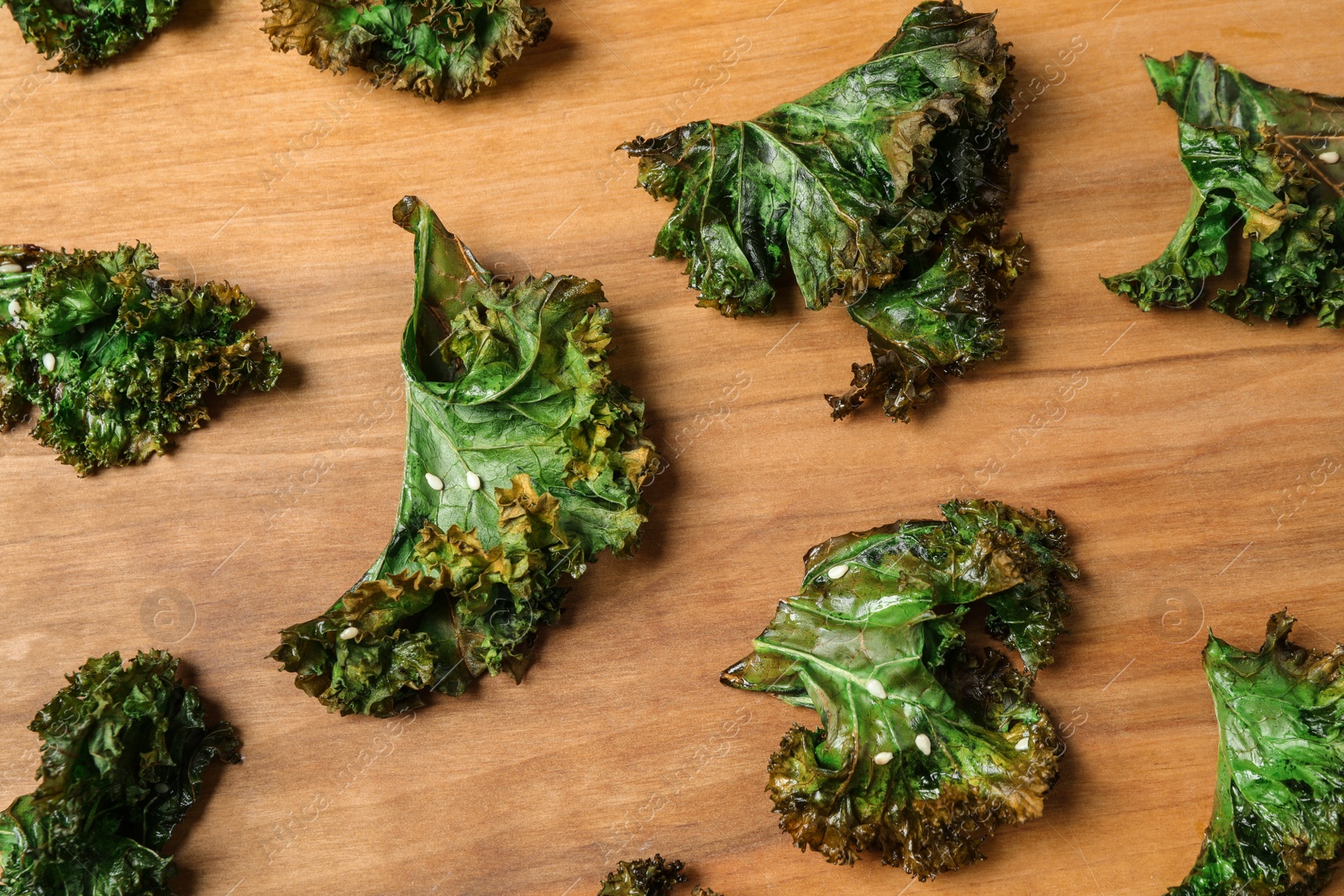 Photo of Tasty baked kale chips on wooden table, flat lay