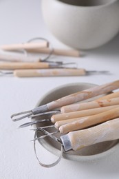 Set of different clay crafting tools on white table