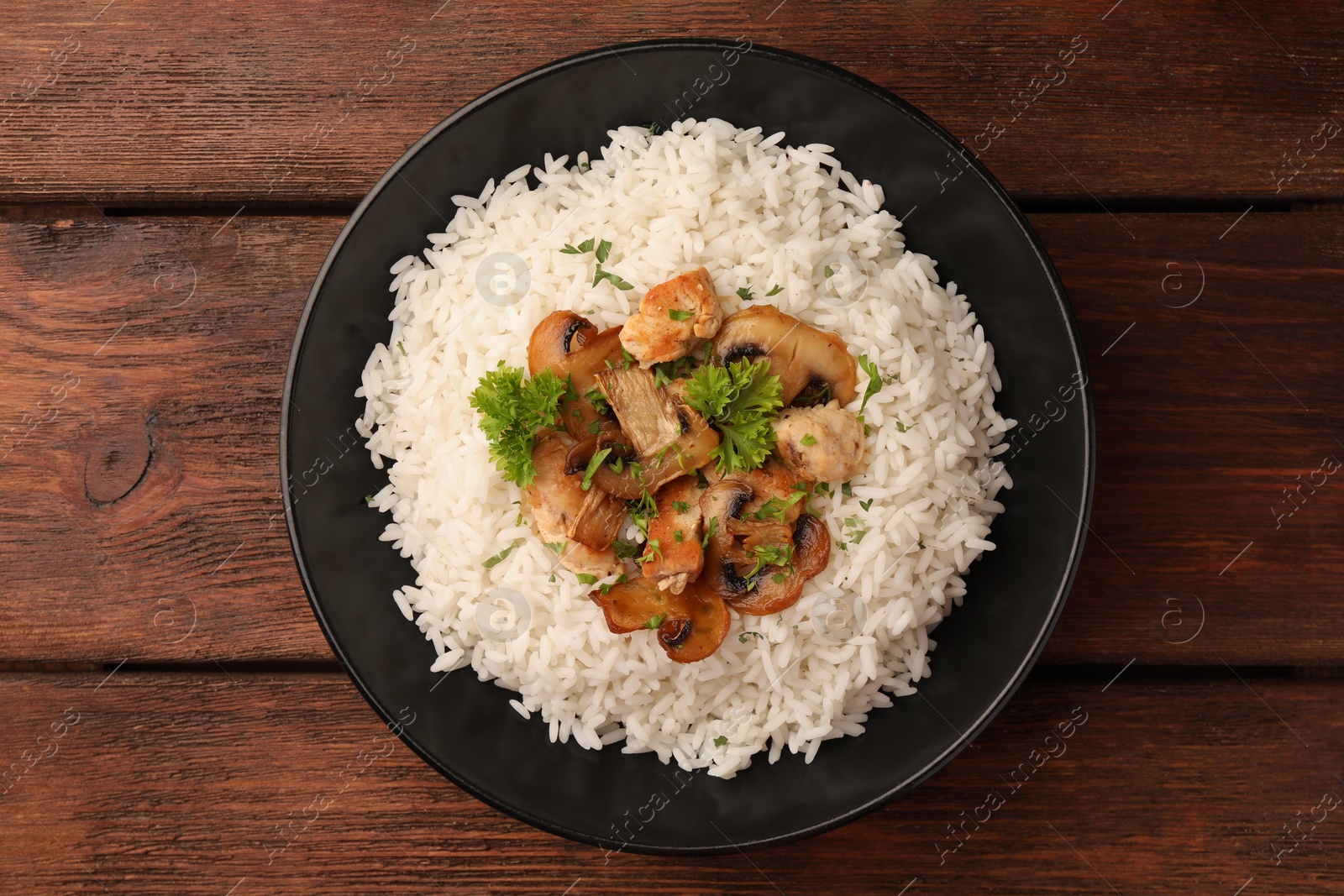 Photo of Delicious rice with mushrooms and parsley on wooden table, top view