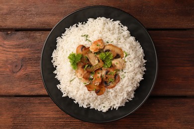 Delicious rice with mushrooms and parsley on wooden table, top view