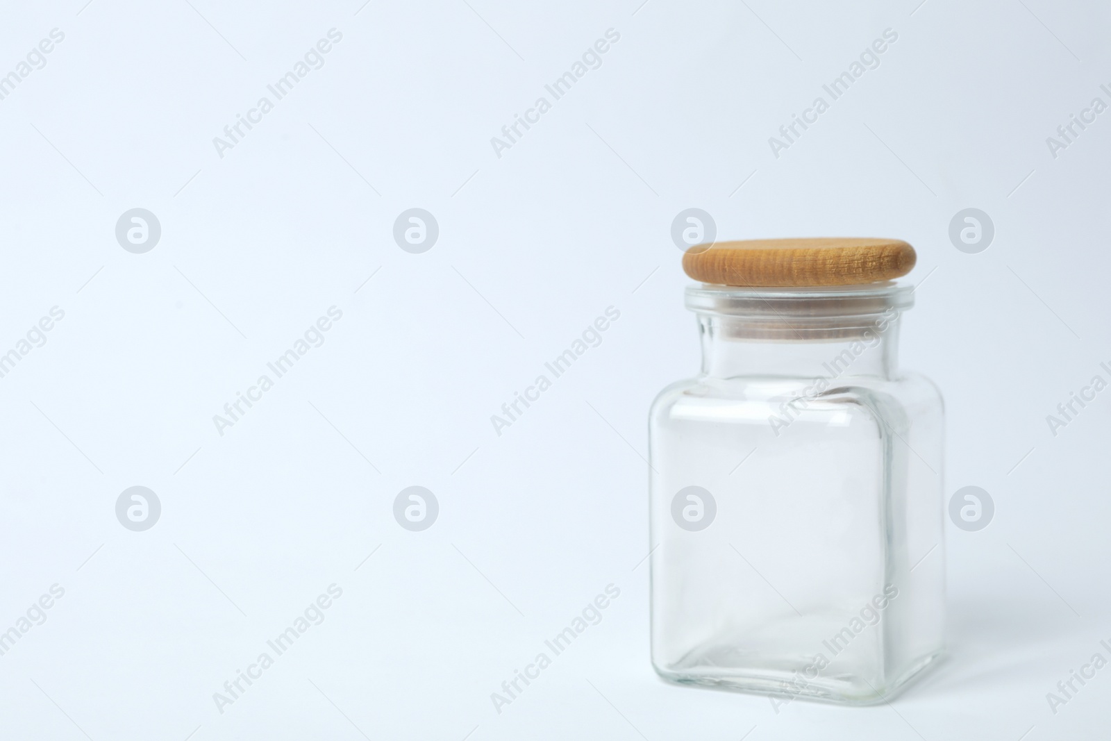 Photo of Closed empty glass jar on light background, space for text