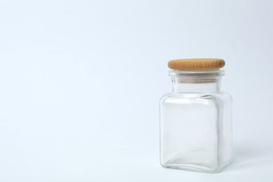 Closed empty glass jar on light background, space for text