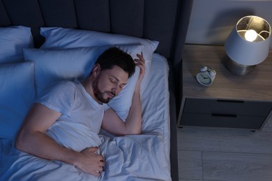 Photo of Man sleeping in bed at night, above view