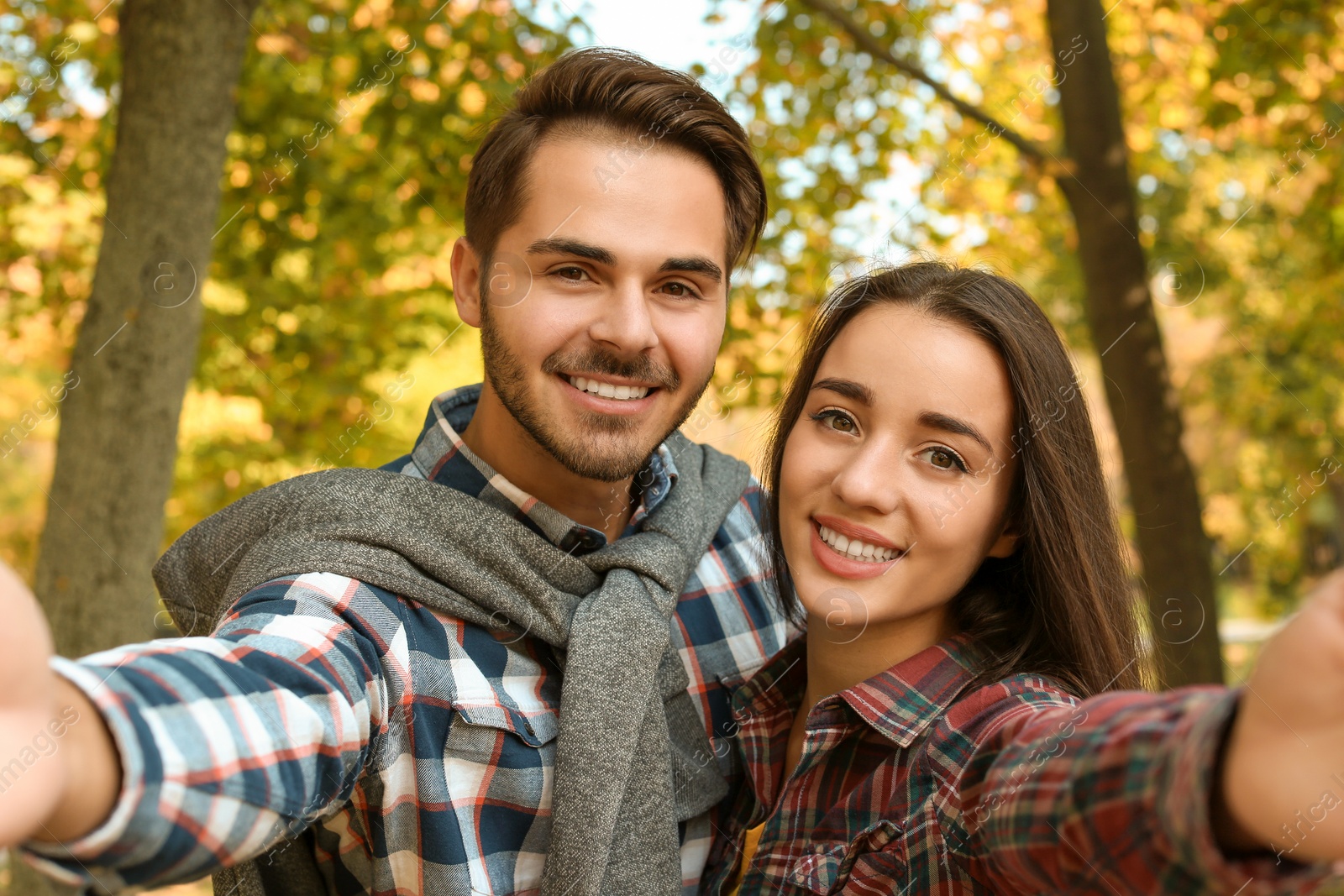 Photo of Young lovely couple taking selfie in park. Autumn walk