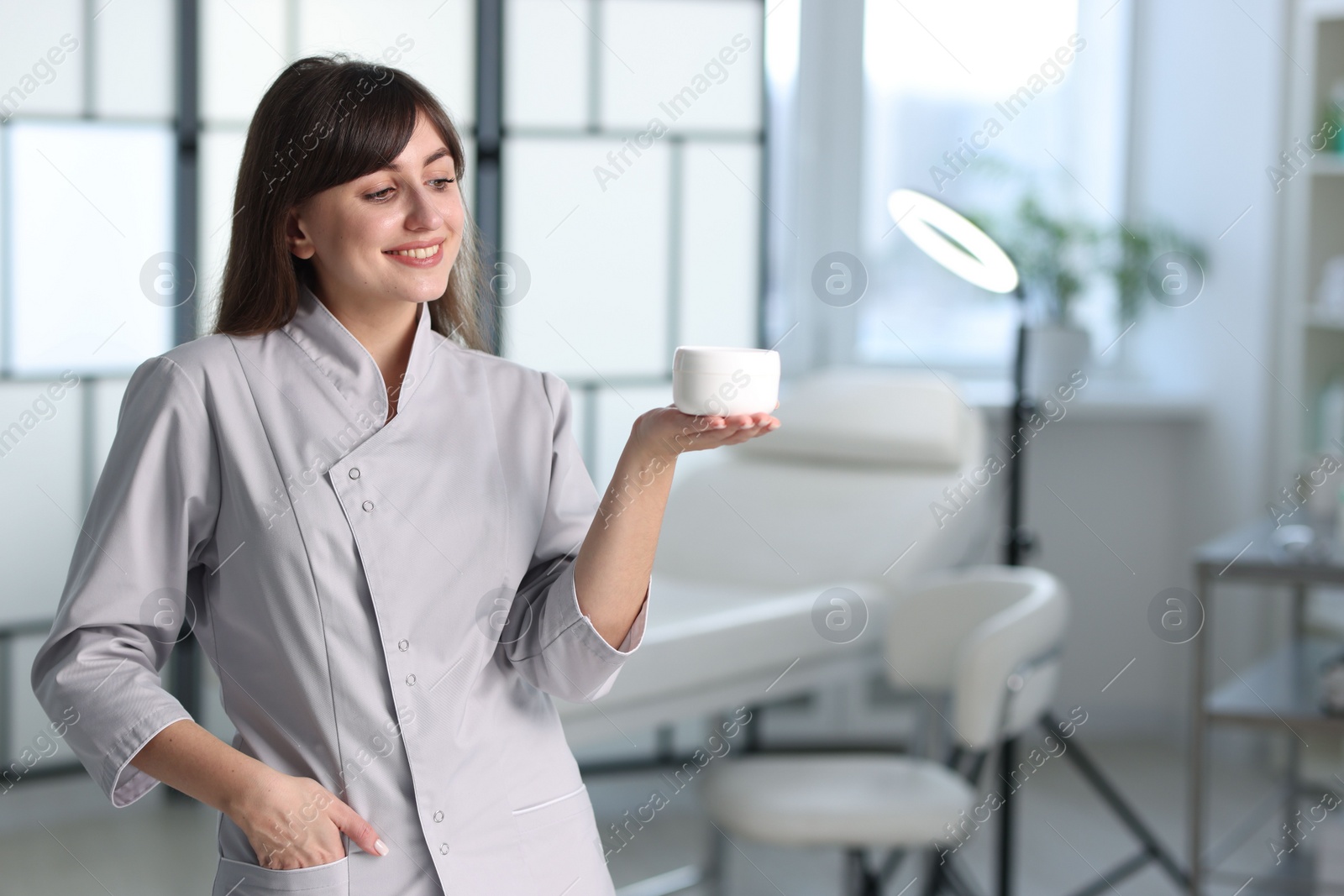 Photo of Cosmetologist with cosmetic product in clinic, space for text