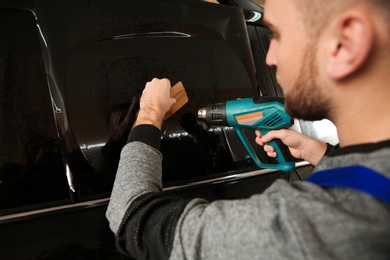 Photo of Skilled worker tinting car window in shop