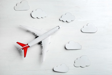 Toy airplane and clouds on white wooden background, flat lay