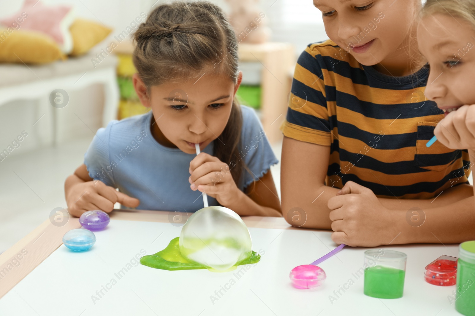 Photo of Children playing with slime at white table indoors