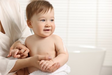 Mother applying body cream onto baby`s skin indoors, closeup. Space for text