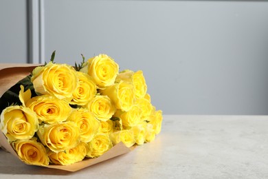 Beautiful bouquet of yellow roses on light grey table, space for text