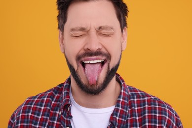 Happy man showing his tongue on orange background