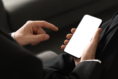 Photo of Man using smartphone with blank screen indoors, closeup. Mockup for design