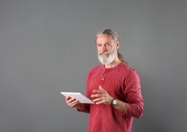 Photo of Portrait of handsome mature man with tablet on color background