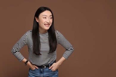 Portrait of smiling woman on brown background. Space for text