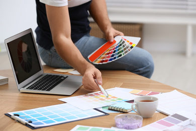Photo of Professional interior designer with color palette at workplace in office, closeup
