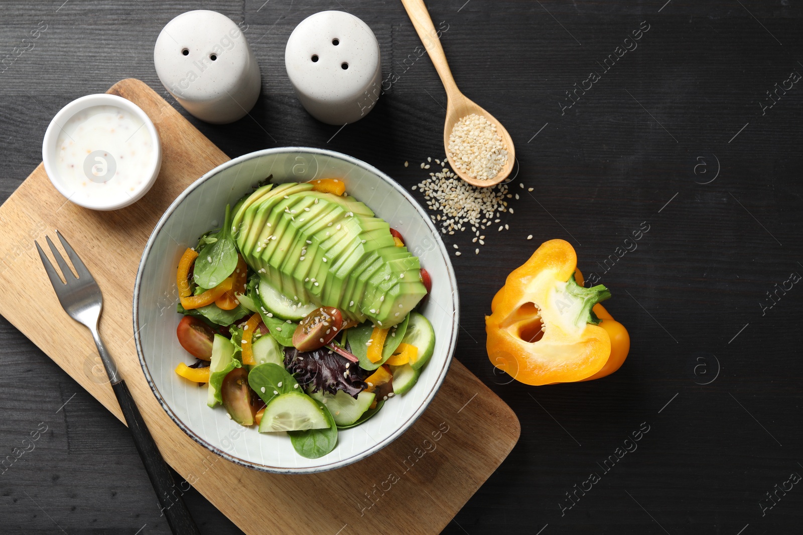 Photo of Healthy dish high in vegetable fats served on black wooden table, flat lay. Space for text