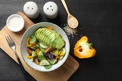 Photo of Healthy dish high in vegetable fats served on black wooden table, flat lay. Space for text