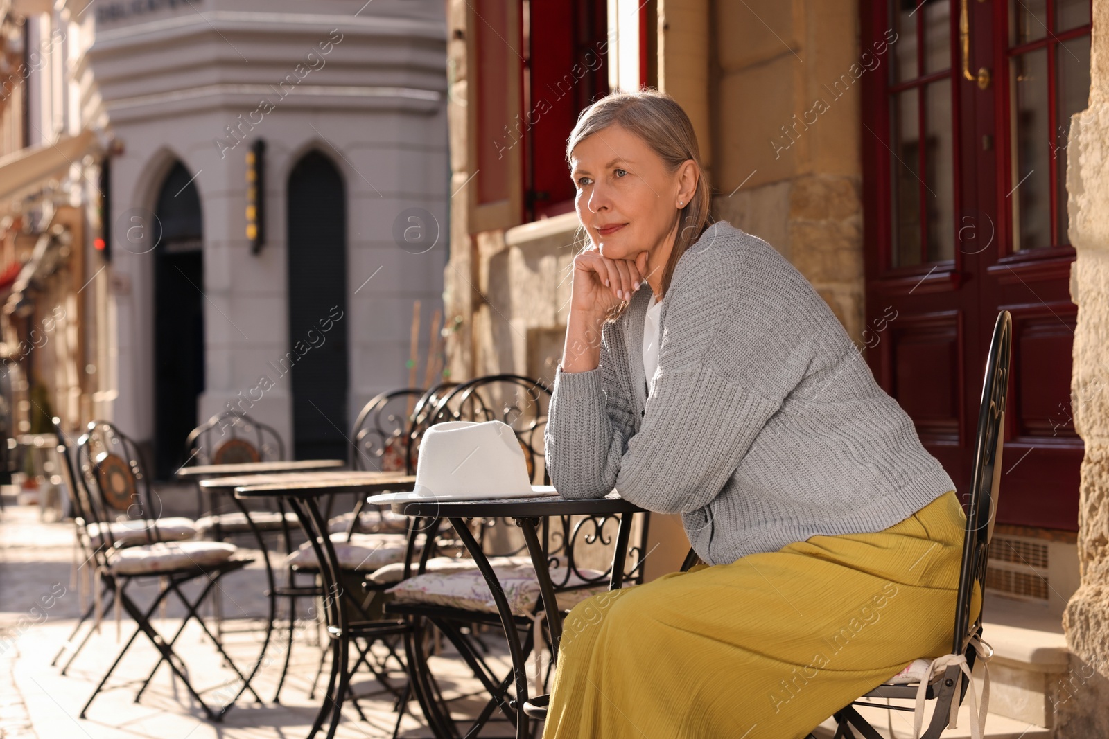 Photo of Beautiful senior woman sitting in outdoor cafe, space for text