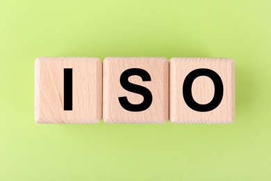 International Organization for Standardization. Wooden cubes with abbreviation ISO on light green background, top view