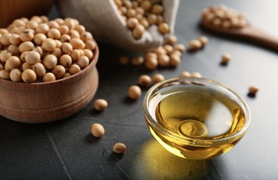 Bowl of oil and soybeans on grey table, closeup