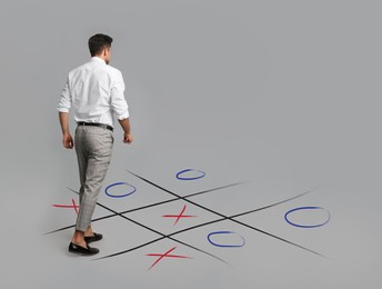 Image of Man and illustration of tic-tac-toe game on grey background, back view. Business strategy concept 