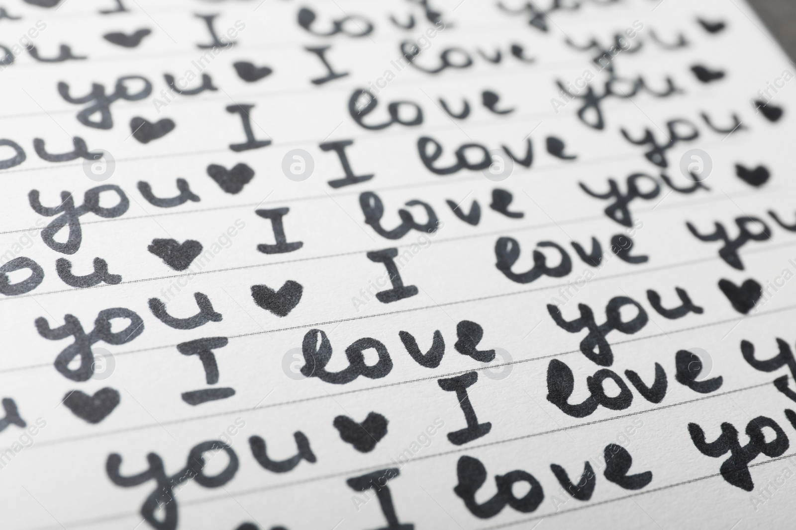 Photo of Notebook page with words I LOVE YOU and hearts as background, closeup