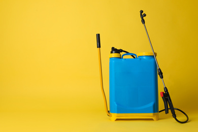 Photo of Manual insecticide sprayer on yellow background, space for text. Pest control