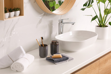 Photo of Toiletries and stylish vessel sink on light countertop in modern bathroom