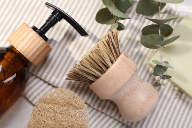 Photo of Cleaning brush, sponge, dispenser, soap bar and eucalyptus leaves on table, top view