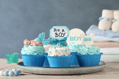 Beautifully decorated baby shower cupcakes for boy with cream on white wooden table