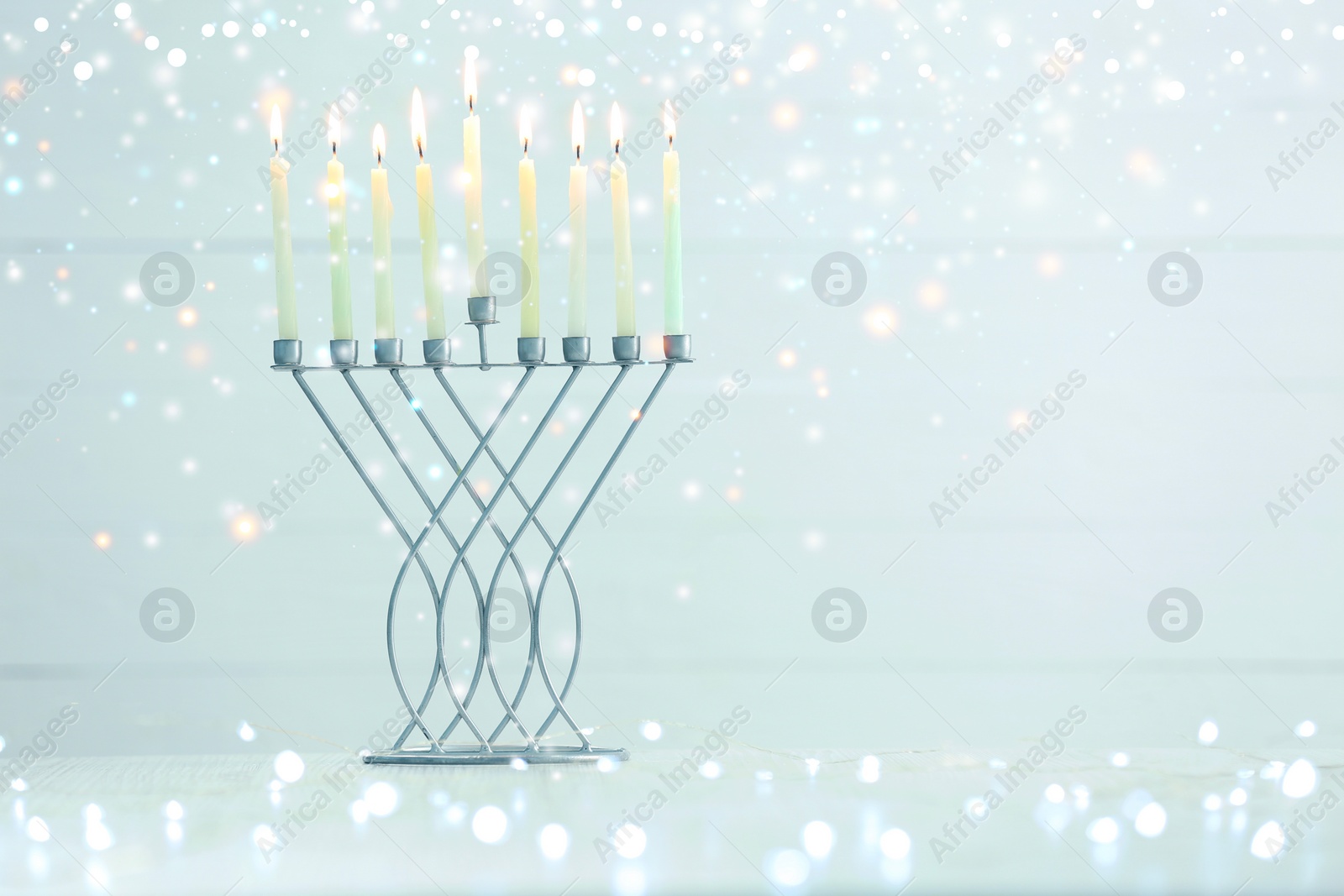 Image of Hanukkah celebration. Menorah with burning candles on table against light background, space for text