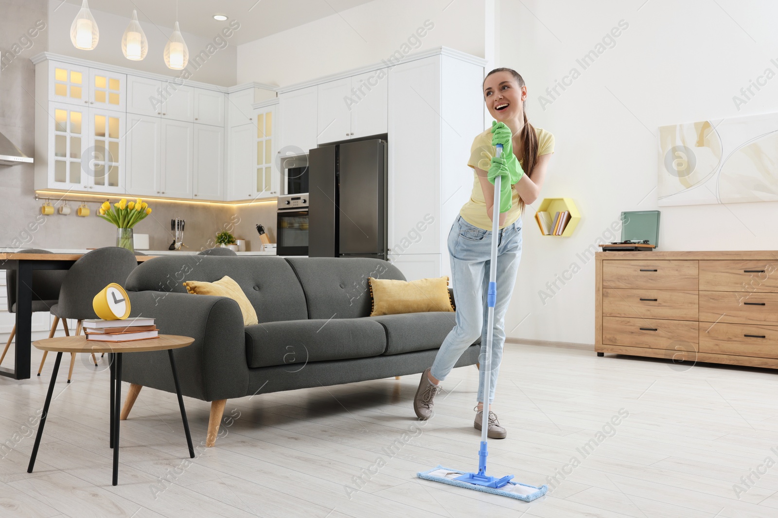 Photo of Spring cleaning. Young woman with mop singing while tidying up at home