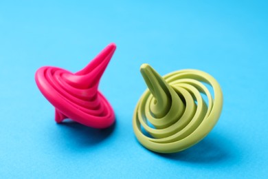 Photo of Pink and green spinning tops on light blue background, closeup