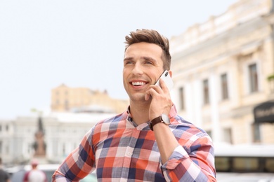 Photo of Attractive young man talking on phone outdoors