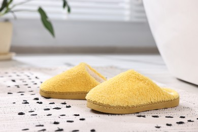 Photo of Yellow soft slippers on carpet at home, closeup