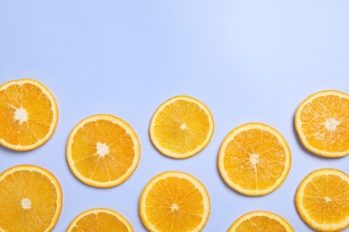 Slices of juicy orange on light blue background, flat lay. Space for text