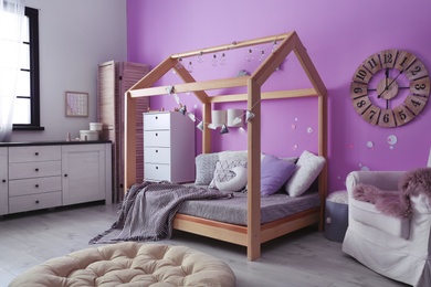 Photo of Child's room interior with comfortable bed and garland