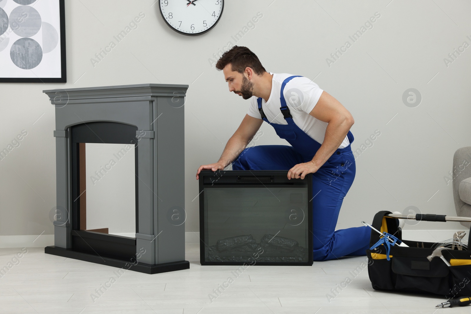 Photo of Professional technician installing electric fireplace in room