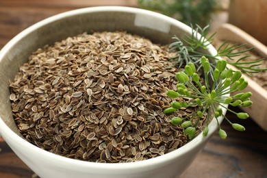 Photo of Bowl of dry seeds and fresh dill on table, closeup